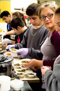 Sajjad Hassan (left) and Alex Paddack (right) serve dinner at the homeless shelter as part of a group led by Julie Foster, a Bridgewater College professor and teacher for healing impaired students at Thomas Harrison school.